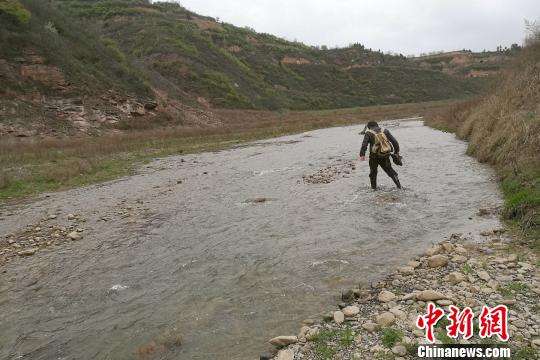 图为童金南教授趟水过河前往剖面。　田力 摄